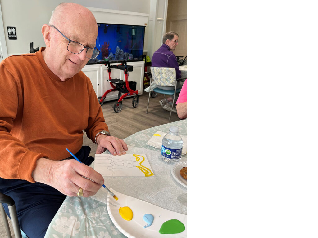 Dan, a Trinity Springs Memory Care resident, paints during an art class focused on creativity and engagement.