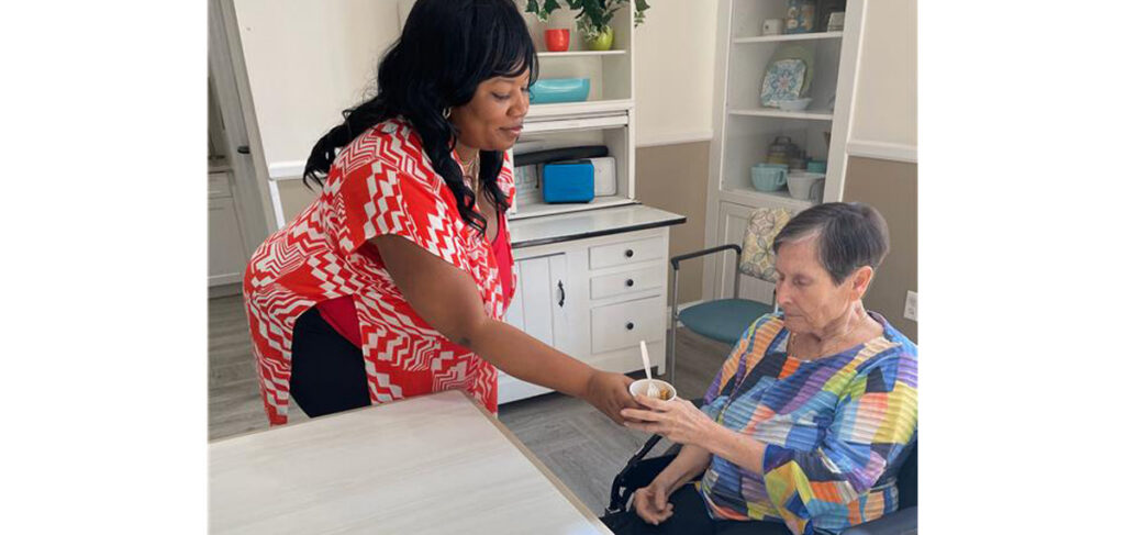 Staff member serves a snack to a memory care resident at Trinity Springs.