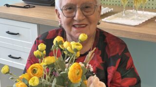Resident engaged in hands on activity during memory care programming at Trinity Springs with floral arrangement.