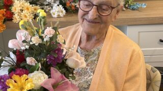 Resident participates in flower arranging activity as part of memory care programming at Trinity Springs.
