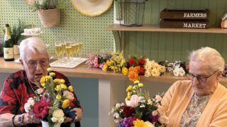 Residents take part in group floral activity in memory care programming at Trinity Springs promoting engagement and connection.