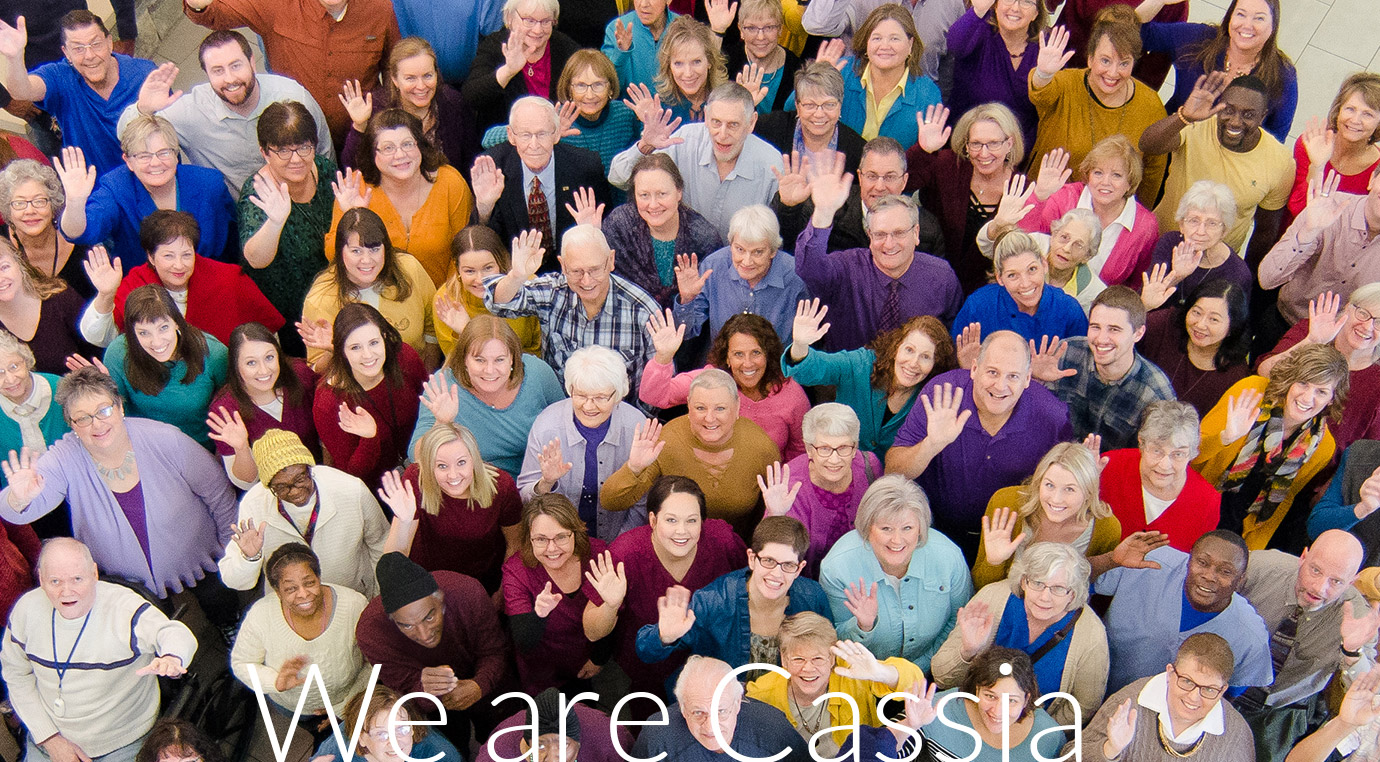 Large group of Cassia employees and community members gathered together and waving toward the camera in a group photo, with the text “We are Cassia” displayed