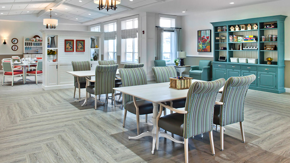 Spacious activity room with tables, upholstered chairs, built-in shelving, and large windows, providing plenty of space for card games, crafts, and group activities at Trinity Springs