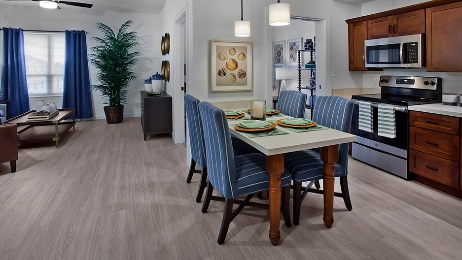 Well-designed apartment with a full kitchen featuring stainless steel appliances, dining area, and open-concept living space at Trinity Springs