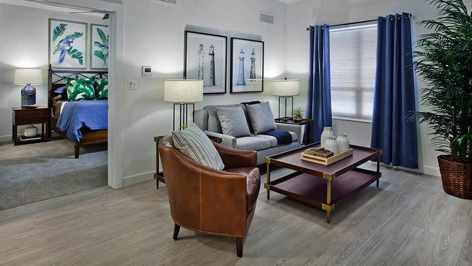 Spacious apartment living room with comfortable seating, large window, bedroom access, and ample space for personal furnishings at Trinity Springs