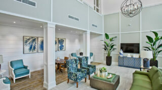 Two-story atrium lobby with lounge seating, conversation areas, decorative lighting, tall ceilings, and large windows at Trinity Springs