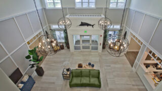 Aerial view of the two-story atrium lobby with decorative chandeliers, lounge seating, reception desk, tall windows, and open gathering spaces at Trinity Springs