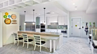 Bistro-style kitchen and dining area with a large island, bar seating, stainless steel appliances, booth seating, and pendant lighting at Trinity Springs