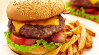 Cheeseburger with lettuce, tomato, bacon, and fries on a plate, representing dining options like at Trinity Springs
