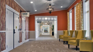 Hallway seating area outside the community movie theater with upholstered chairs, large windows, decorative lighting, and access to nearby amenities at Trinity Springs