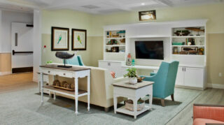 Coastal-themed lounge with sofa seating, armchairs, built-in entertainment center, television, decorative shelving, and gathering space at Trinity Springs