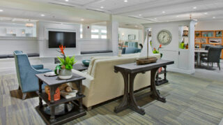 Community lounge with sofa seating, armchairs, television, built-in shelving, tables, and adjacent gathering spaces in a comfortable common area at Trinity Springs