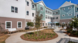 Landscaped courtyard with walking paths, patio seating, umbrellas, benches at Trinity Springs