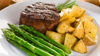 Grilled steak with asparagus and roasted potatoes on a dinner plate, representing chef-prepared dining options like at Trinity Springs