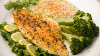 Seasoned fish fillet served with broccoli, rice, and lemon slices, representing chef-prepared dining options like at Trinity Springs