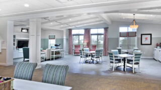 Open dining and lounge area with tables, upholstered chairs, large windows, television seating, and comfortable gathering spaces at Trinity Springs