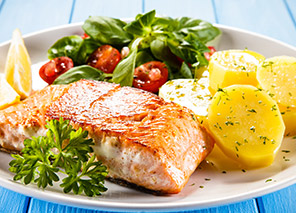 Grilled salmon with roasted potatoes, mixed greens, cherry tomatoes, and lemon, representing chef-prepared dining options like at Trinity Springs