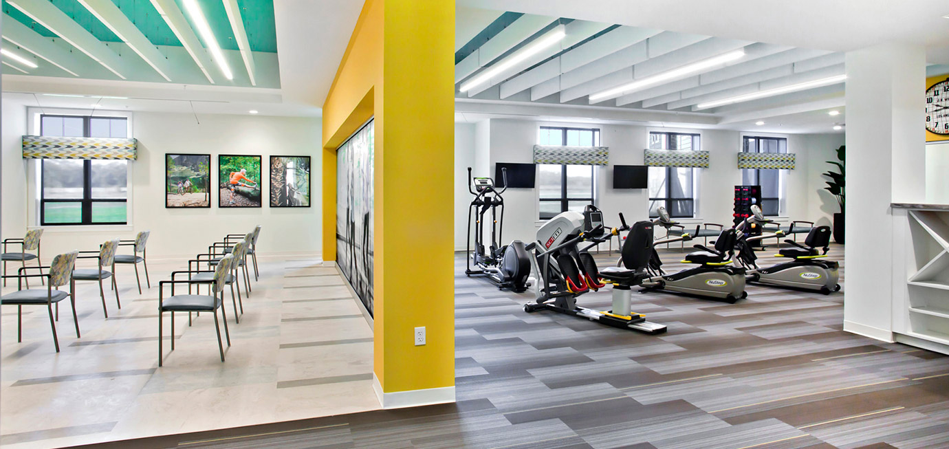 Fitness center with cardio equipment, exercise machines, and a group fitness area with chairs in a bright wellness space at Trinity Springs