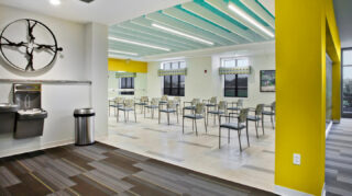 Fitness classroom with rows of chairs, mirrored exercise wall, large windows, hydration station, and open space for wellness classes at Trinity Springs
