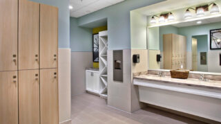 Fitness center locker room with storage lockers, vanity sinks, mirrors, built-in shelving, and changing area amenities at Trinity Springs