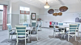 Gathering room with tables, chairs, built-in bench seating, decorative wall accents, and large windows at Trinity Springs