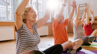 Group of older adults participating in a fitness class with raised arms, representing wellness programs and group exercise opportunities like at Trinity Springs