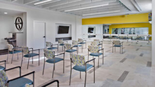 Group fitness room with chairs arranged for exercise classes, mirrored wall, fitness barres, televisions, and open space for wellness programs at Trinity Springs