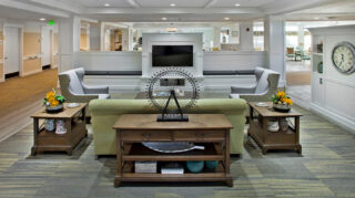 Community lounge with sofa seating, armchairs, wall-mounted television, decorative furnishings, and open gathering areas at Trinity Springs