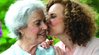 Older adult and another adult sharing a close moment outdoors, representing family connection and memory care support like at Trinity Springs