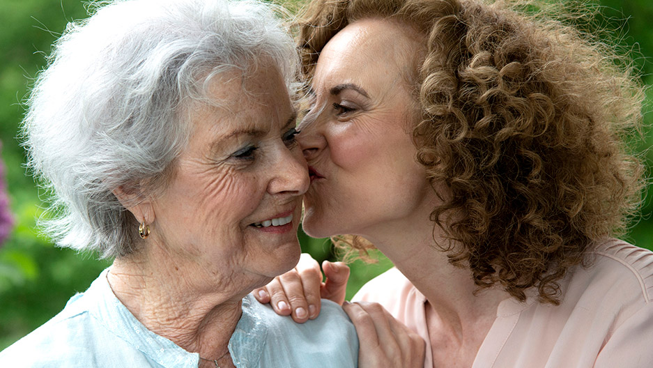 Older adult and another adult seated closely together outdoors, representing family connection and memory care support like at Trinity Springs
