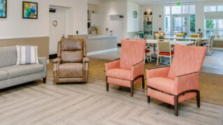 Memory care gathering space with armchairs, sofa seating, dining tables, large windows, and open common areas designed for comfort and social engagement at Trinity Springs