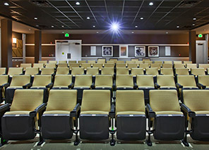 Movie theater with rows of comfortable theater seating, large projection screen, acoustic wall panels, and surround-sound entertainment space at Trinity Springs