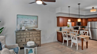 Open-concept apartment with a full kitchen, stainless steel appliances, dining table, spacious living area, and modern finishes at Trinity Springs