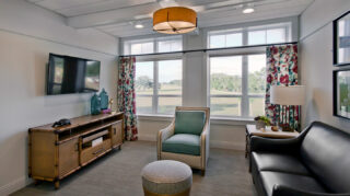Private lounge with sofa seating, armchair, wall-mounted television, large windows, and outdoor views in a comfortable gathering space at Trinity Springs
