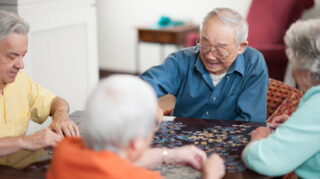 Group of older adults working together on a jigsaw puzzle around a table, representing social activities and cognitive engagement like at Trinity Springs