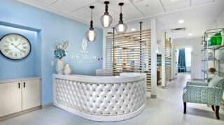 Salon reception area with check-in desk, decorative lighting, comfortable seating, service rooms, and salon signage at Trinity Springs