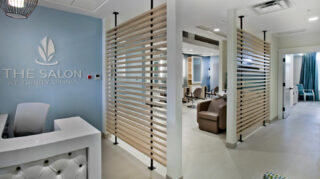 Salon with styling stations, salon chairs, wash stations, reception area, and private treatment rooms offering personal care services at Trinity Springs