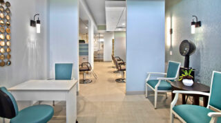 Salon with seating, styling stations, hair dryers, side tables, and personal care services space at Trinity Springs