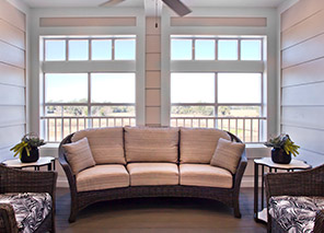 Screened lanai with cushioned sofa seating, side tables, large windows, ceiling fan, and scenic outdoor views at Trinity Springs