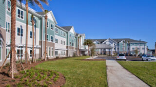 Walking path alongside landscaped grounds, palm trees with covered outdoor areas at Trinity Springs