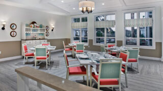 Dining room with tables, chairs, place settings, decorative cabinetry, and large windows overlooking the courtyard at Trinity Springs