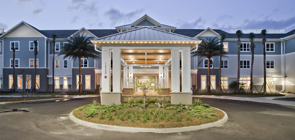 Senior living community entrance with covered portico and landscaped driveway.